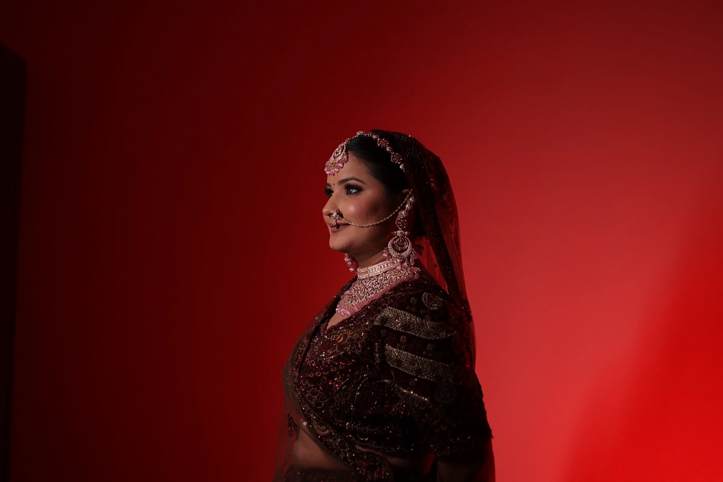 Bride in profile against a deep red backdrop